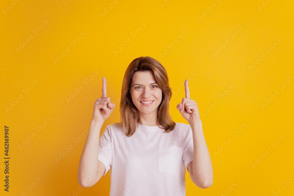 Photo of positive lady indicate finger up empty space discount option wear casual clothes on yellow background Photo of positive lady indicate finger up empty space discount option wear casual clothes on yellow background
