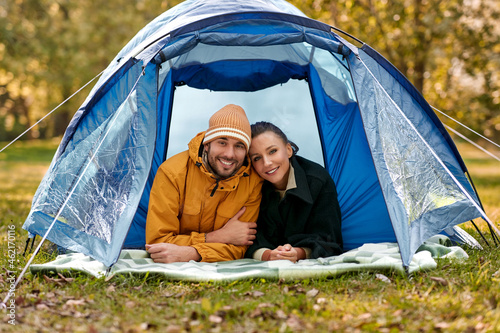 camping, tourism and travel concept - happy couple lying inside tent at campsite