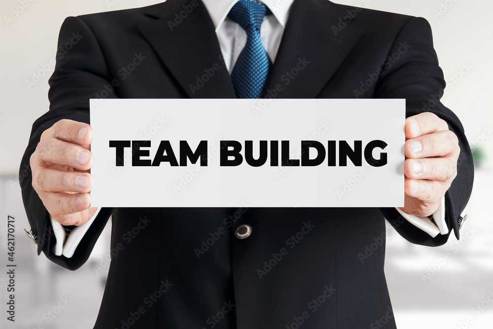 Businessman shows a banner with the message team building. Business teamwork or team formation Businessman shows a banner with the message team building. Business teamwork or team formation