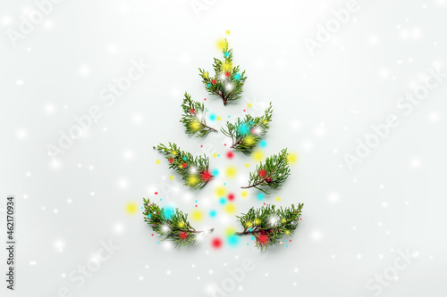 Minimalistic Christmas tree made of green branches and snowflakes decorations on a white background.