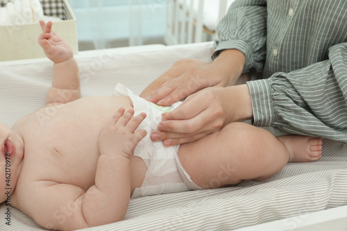 Mother changing baby s diaper on table at home  closeup