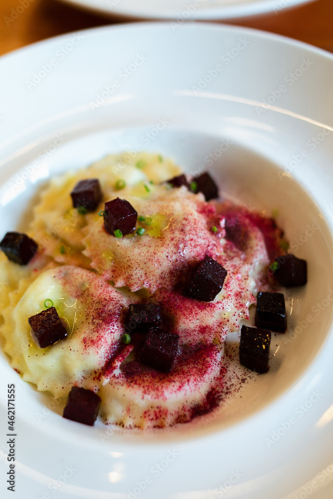 Demonstration of a ready-made dish in a modern style. Ravioli garnished with svela cubes and beetroot dust, chopped green onion rings. Italian cooking technique. Demonstration of a ready-made dish in a modern style. Ravioli garnished with svela cubes and beetroot dust, chopped green onion rings. Italian cooking technique.