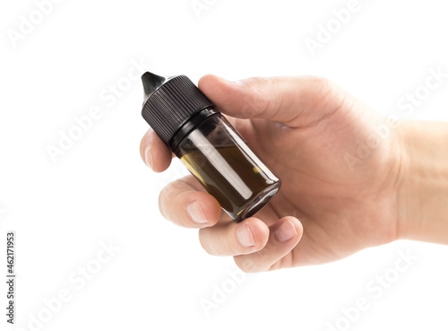 The hand holds an bottle of liquid for an electronic cigarette. Close up