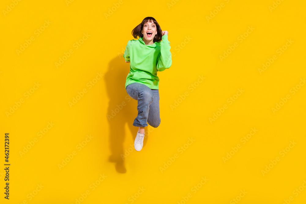 Full length body size view of attractive cheerful girl jumping running marathon isolated over bright yellow color background Full length body size view of attractive cheerful girl jumping running marathon isolated over bright yellow color background