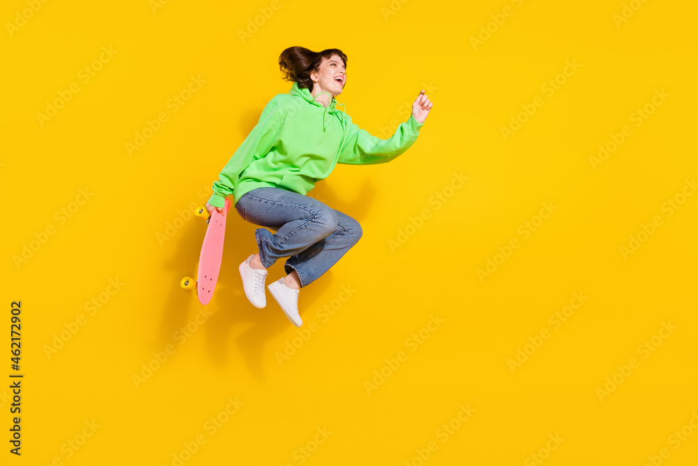 Full body photo of attractive young happy lady jump up skater longboard isolated on yellow color background