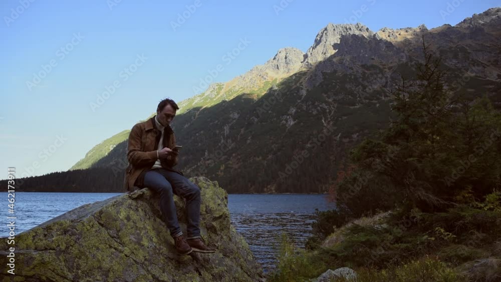 Climbing on the rock at mountain lake. Hiking traveling tourist in the mountains along. Adventure journey exploring the mountains. Climbing on the rock at mountain lake. Hiking traveling tourist in the mountains along. Adventure journey exploring the mountains.