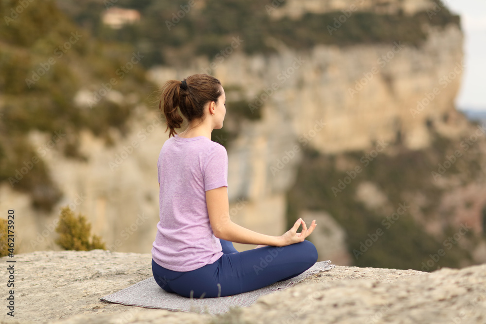 Woman alone doing yoga in a cliff