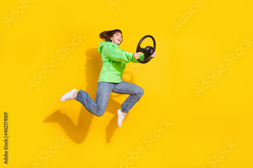 Full length body size view of attractive cheery girl jumping holding steering wheel having fun isolated over bright yellow color background