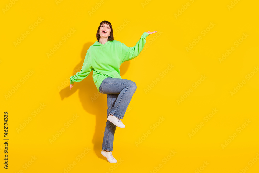 Full length body size view of pretty cheerful girl dancing having fun posing welcome isolated over bright yellow color background Full length body size view of pretty cheerful girl dancing having fun posing welcome isolated over bright yellow color background