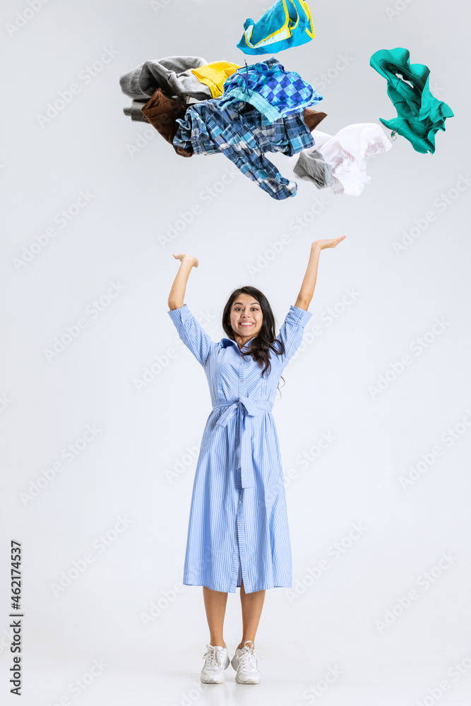 Fototapeta premium One beautiful young girl shopping while black friday sales. Model standing under the clothes falling from above isolated over white background.