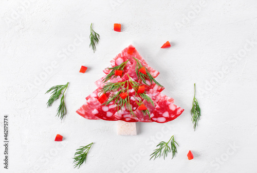 Canape, Christmas tree, with salami on wheat bread topped with dill and pepper on the white table. Top view. Festive appetizer. New Year table setting photo