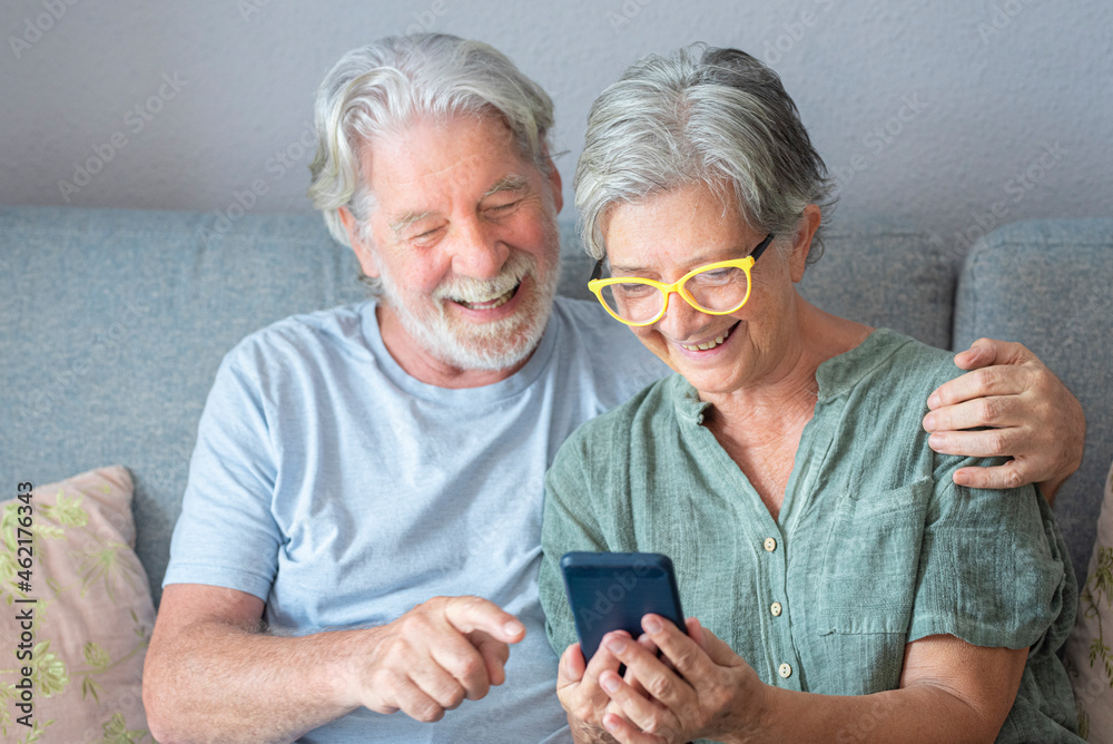 Happy senior man gesturing during video call by woman sitting on sofa Happy senior man gesturing during video call by woman sitting on sofa