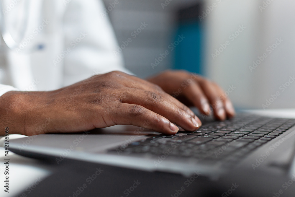 Closeup of african american doctor hand typing healthcare treatment on laptop computer keyboard after analyzing sickness expertise. Practitioner working in hospital office. Health care service Closeup of african american doctor hand typing healthcare treatment on laptop computer keyboard after analyzing sickness expertise. Practitioner working in hospital office. Health care service