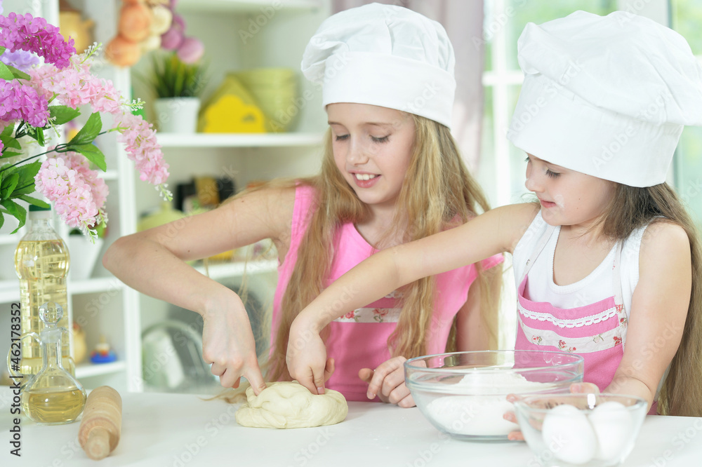 Cute little girls in chefs hats making dough Cute little girls in chefs hats making dough