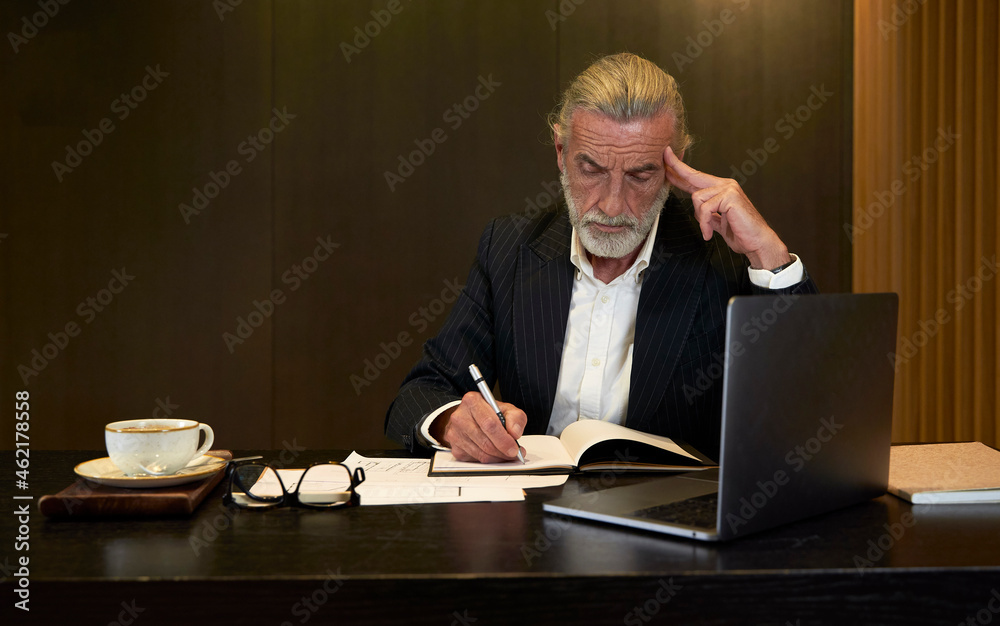 Businessman writing in diary while working at desk in hotel