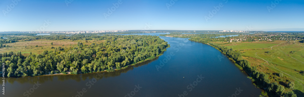 Section of wide plain river with distant city, aerial view