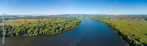 Section of wide plain river with distant city, aerial view