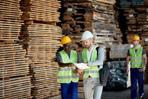 Young black worker and inspector go through paperwork while walking through warehouse.