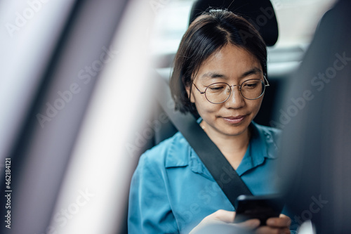 Close-up image of a businesswoman in the car using smart phone.