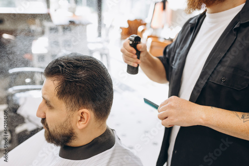 Man getting haircut at the barbershop. Professional barber at work process. Beauty, selfcare, style, fashion, healthcare and male cosmetics concept.