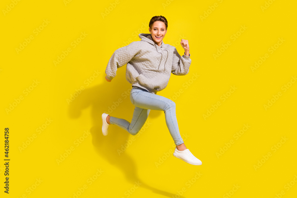 Full length photo of cool brown hair millennial lady run wear sweater jeans sneakers isolated on yellow background