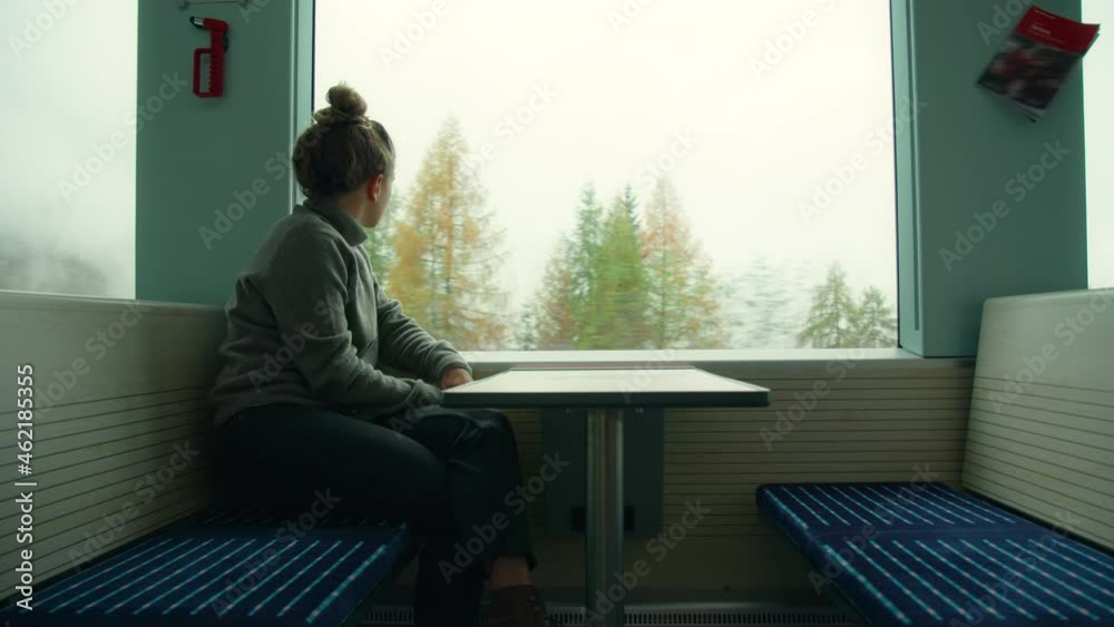 Cinematic shot of young woman travel alone in train car, look out of window on scenic mountain landscape. Inspiring travel wanderlust. Travel blogger, passenger on early morning commute train Cinematic shot of young woman travel alone in train car, look out of window on scenic mountain landscape. Inspiring travel wanderlust. Travel blogger, passenger on early morning commute train