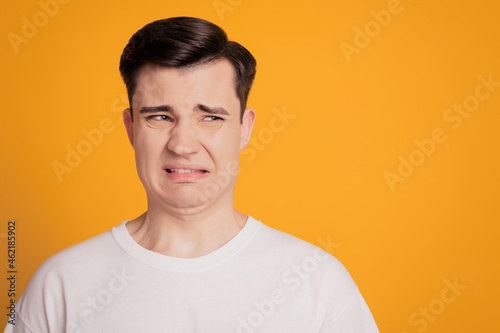 Portrait of crazy mad angry disgusted guy frown grimace look side blank space on yellow background