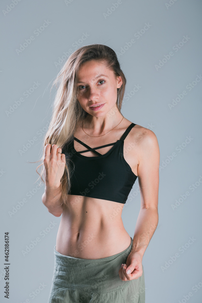 Naklejka premium Fitness girl with sporty body posing at studio on grey background. Fitness smiling model in sportswear. Weight Loss. Healthy lifestyle. Sporty healthy female.