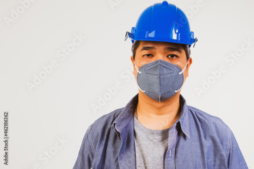 The handsome male worker wore a blue helmet and a dust mask to prevent PM2.5 and the epidemic COvid-19.