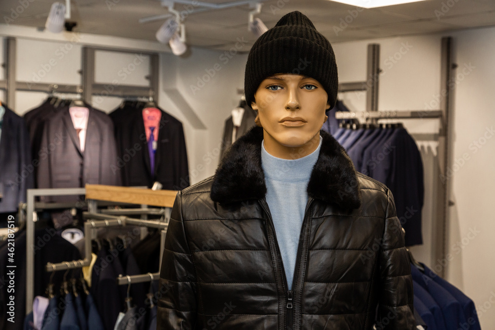 The male mannequin is dressed in fall, winter clothes, a gray turtleneck and a black hat. He is looking at the camera.