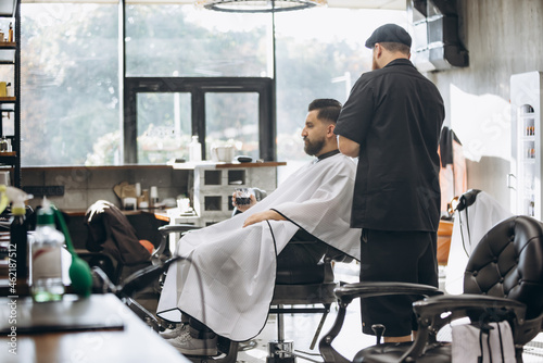 Man getting haircut at the barbershop. Professional barber at work process. Beauty, selfcare, style, fashion, healthcare and male cosmetics concept. © master1305