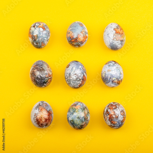 Colorful easter eggs painted in natural products blueberries and onion peels, isolated on yellow background