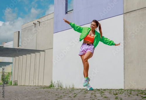 Young happy woman with arms outstretched dancing on footpath