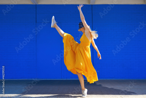 Carefree woman dancing by blue wall on sunny day photo