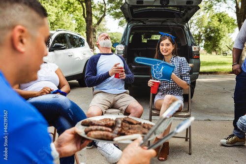 Man handing out burgers at a tailgate party photo