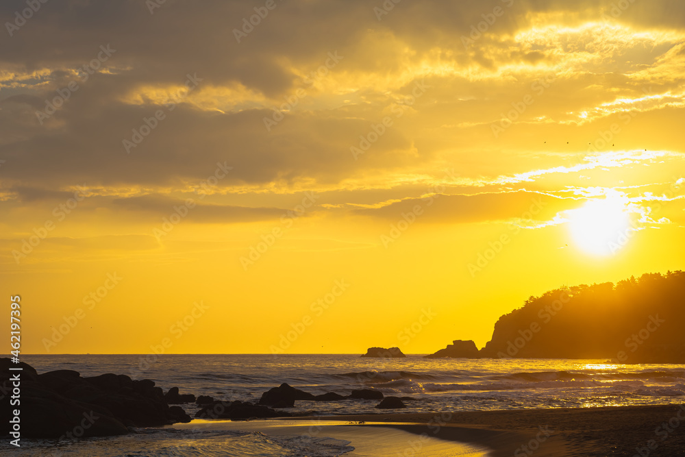 바닷가 바위와 일출 금빛 태양으로 빛나는 풍경