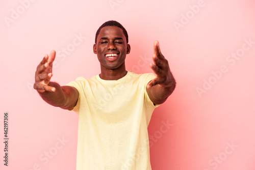 Young African American man isolated on pink background celebrating a victory or success, he is surprised and shocked.