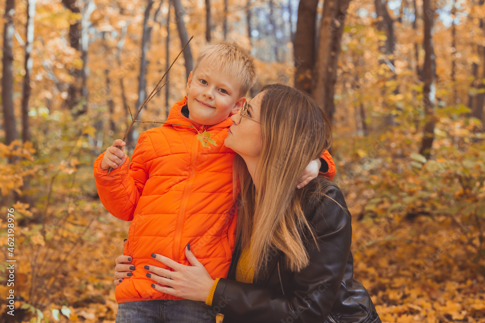 Mother hugging her child during walk in autumn park. Fall season and single parent concept. Mother hugging her child during walk in autumn park. Fall season and single parent concept.