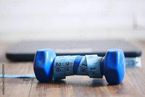 Fitness concept with dumbbell, measurement tape and weight scale on floor 