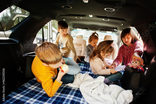 Mother with four kids at vehicle interior. Children in trunk. Traveling by car, lying and having fun, atmosphere concept.