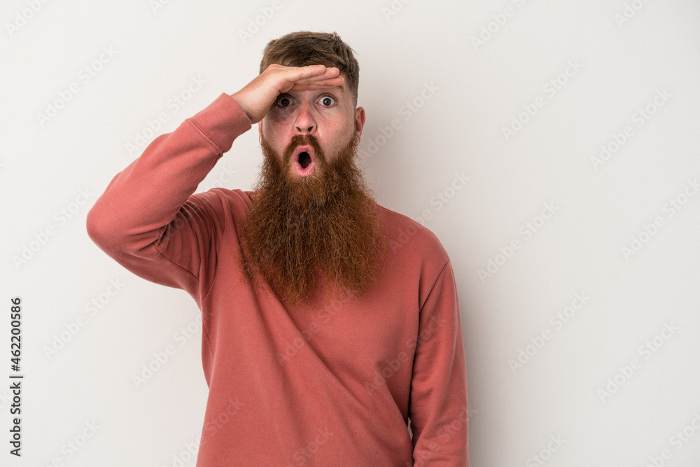 Young caucasian ginger man with long beard isolated on white background looking far away keeping hand on forehead. Young caucasian ginger man with long beard isolated on white background looking far away keeping hand on forehead.