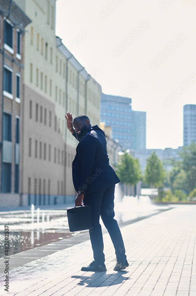 A tall dark-skinned man in a suit in the street