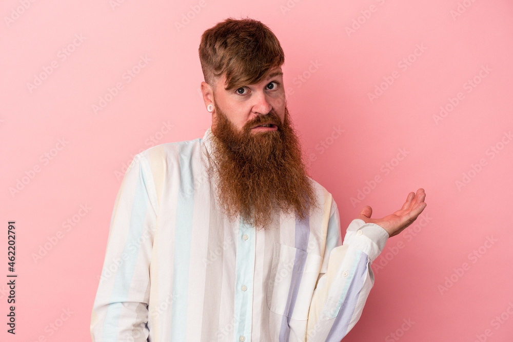 Young caucasian ginger man with long beard isolated on pink background doubting and shrugging shoulders in questioning gesture. Young caucasian ginger man with long beard isolated on pink background doubting and shrugging shoulders in questioning gesture.