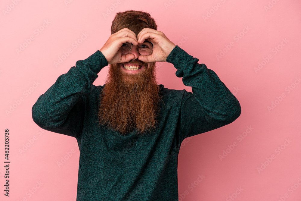 Young caucasian ginger man with long beard isolated on pink background showing okay sign over eyes Young caucasian ginger man with long beard isolated on pink background showing okay sign over eyes