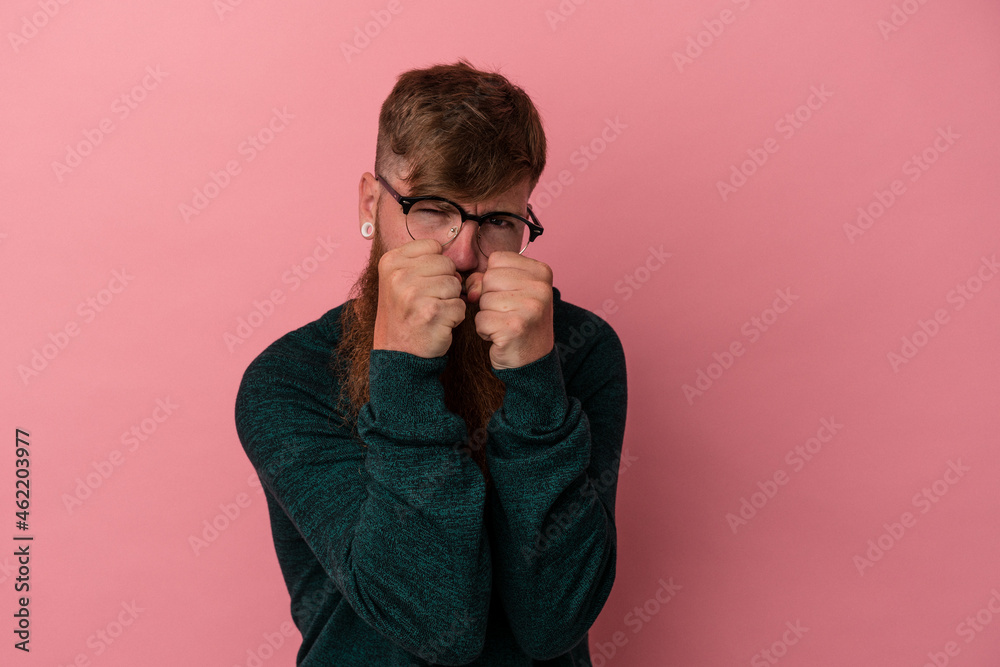 Young caucasian ginger man with long beard isolated on pink background throwing a punch, anger, fighting due to an argument, boxing. Young caucasian ginger man with long beard isolated on pink background throwing a punch, anger, fighting due to an argument, boxing.