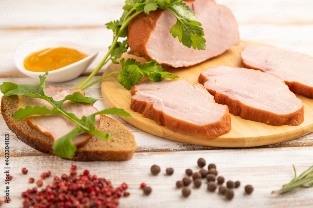 Smoked pork ham on cutting board on white wooden background. Side view, close up, selective focus.