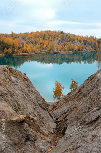 A vertical view of a picturesque turquoise lake against the backdrop of an autumn forest. Romantsevskie rocks