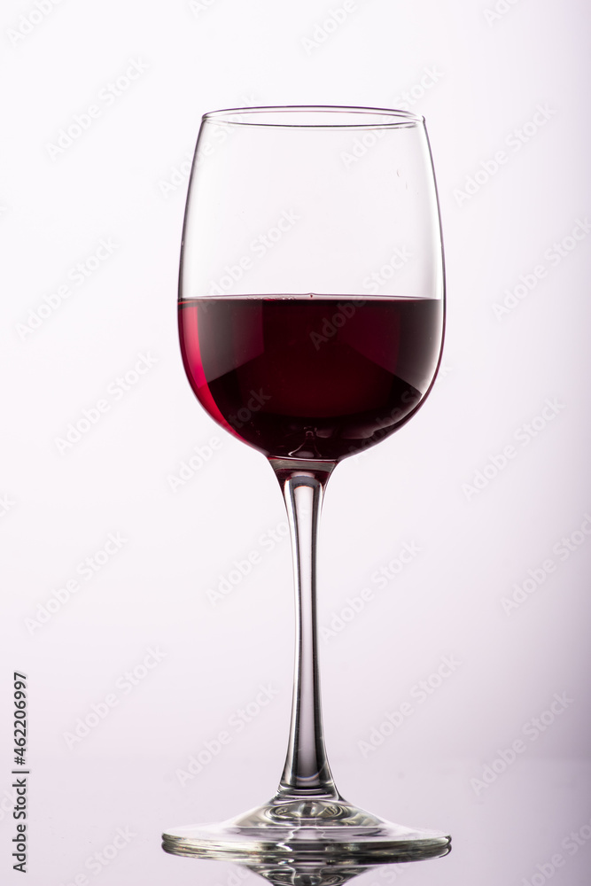 pouring red wine into glass with highlights on red background pouring red wine into glass with highlights on red background