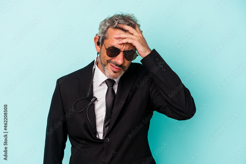 Middle age bodyguard caucasian man isolated on blue background being shocked, she has remembered important meeting. Middle age bodyguard caucasian man isolated on blue background being shocked, she has remembered important meeting.
