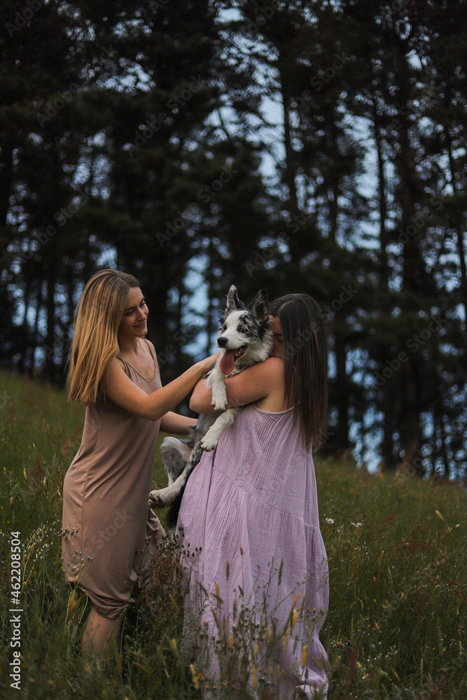 Naklejka premium young women kissing and hugging her dog in nature